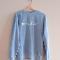 Stay You crewneck in Pigment Old South Blue hanging on a wooden hanger